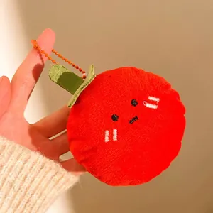 Gros plan d'un porte-clés peluche de nourriture rouge avec visage brodé et chaînette