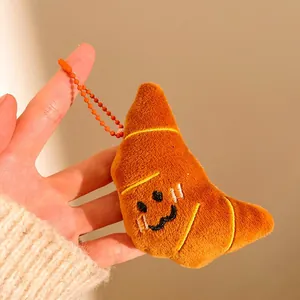 Gros plan d'un porte-clés croissant en peluche avec un sourire, tenu dans la main