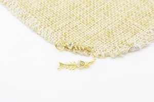 Vue détaillée de deux breloques arêtes de poisson dorées sur fond de toile de jute rustique