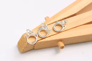 Close-up of three small sterling silver cat head charms for DIY jewelry making
