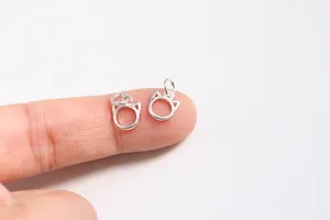 Macro shot of tiny S925 sterling silver cat head charms on a fingertip for DIY jewelry