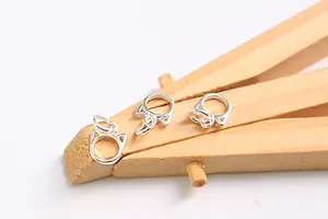Macro shot of three silver cat head charms with jump rings on a rustic wooden clip