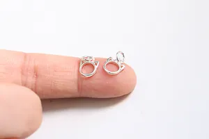 Macro shot of silver hollow cat-ear charm pendants for DIY jewelry making on fingertip