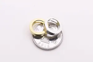 Vista macro di anelli cavi opachi in oro e argento accanto a una moneta per riferimento