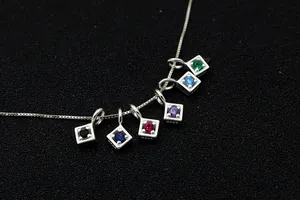 Macro shot of S925 sterling silver charms with multi-colored zircons on a simple box chain