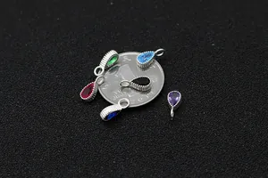 Macro view of S925 silver teardrop gemstone pendants in multiple colors on a coin