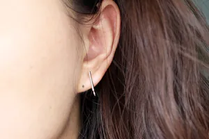 Close-up of S925 sterling silver bar stud earrings with small loops on female ear