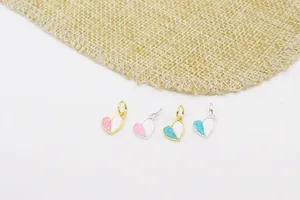 Macro-detail van hartvormige DIY-hangers met roze en wit emaille in gouden afwerking
