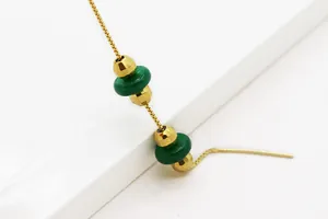 Dettaglio di orecchini a catena placcati in oro con perle verdi in stile malachite