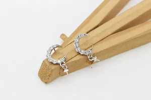 Detalle de pendientes de luna plateada con circonitas para creación de joyas artesanales
