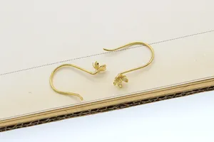 Detailed macro view of golden flower petal earrings with curved U-shaped hooks