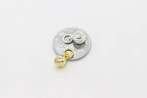 Détails de pendentifs lanternes évidés en argent et or avec zircon à côté d'une pièce