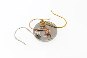 Macro detail of S925 sterling silver petal flower ear hooks with a coin for scale reference