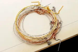 Dettaglio di bracciali regolabili in oro, argento e oro rosa con finitura glitterata