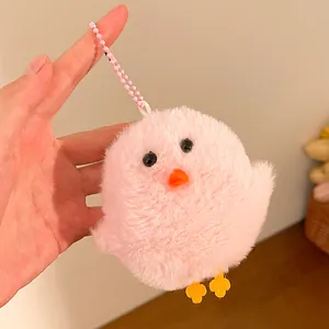Close-up of pink plush chick keychain held in hand showing soft texture and bead chain