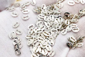 Macro shot of S925 sterling silver oval tags for jewelry making in hand with white glove