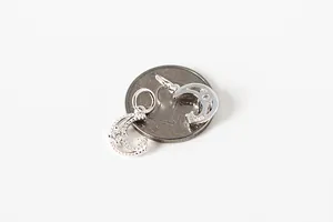 Detailed view of S925 sterling silver moon pendants with zircon beside a coin for size
