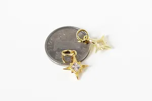 Macro view of gold-plated star pendant with cubic zirconia next to a coin for size scale