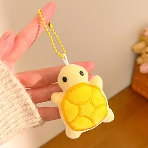 Close-up of plush cartoon turtle keychain with soft yellow fabric and detailed embroidery