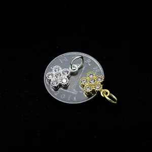 Pendente a fiore in argento S925 con zirconi accanto a una moneta per scala dimensionale
