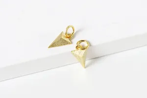 Détail macro de pendentifs triangulaires en or mat avec finition texturée pour bijoux