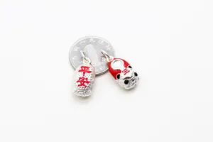Macro detail of S925 silver tiger shoes charm with red enamel and coin for scale