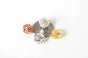 Macro detail of S925 silver hollow spacer beads in gold and rose gold beside a coin