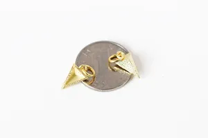 Détails macro de pendentifs triangles pyramides dorés givrés avec anneaux près d'une pièce