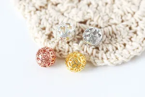 Macro shot of 4-color hollow sterling silver spacer beads with intricate floral coin patterns