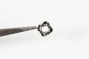 Macro detail of retro S925 silver cube bead with embossed floral pattern for DIY jewelry