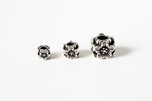 Close-up of three vintage S925 silver floral cube beads for DIY jewelry making