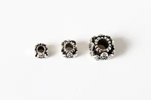 Macro detail of three vintage floral engraved S925 sterling silver square spacer beads