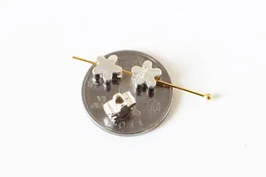 Macro detail of S925 sterling silver flower beads on a coin for size reference