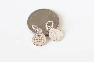Vue macro de breloques en argent sterling 925 avec détails en relief vintage près d'une pièce