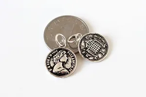 Détail de breloques en argent sterling S925 à l'effigie de la reine près d'une pièce d'un yuan