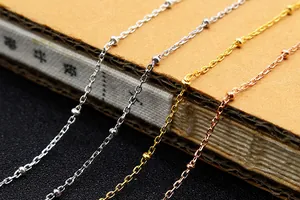 Macro detail of S925 sterling silver beaded cross chains in four metallic finishes