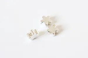 Macro detail of three silver flower beads with center holes for DIY jewelry crafting