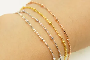 Macro shot of minimalist S925 sterling silver beaded cross chains in four metallic finishes