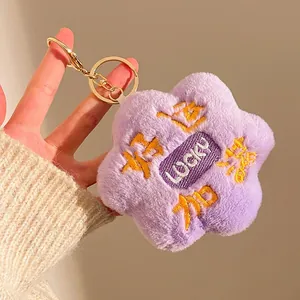 Close-up of purple plush flower keychain with Lucky embroidery and gold metal ring