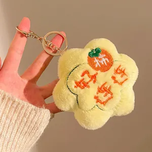 Close-up of yellow plush flower keychain with Persimmon Good Luck embroidery and gold clip