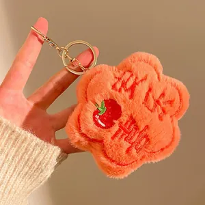 Detail of soft orange plush flower keychain with embroidered apple and golden ring