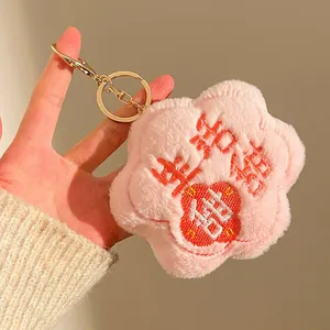 Detailed view of plush flower keychain with golden ring and red Chinese embroidery