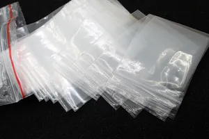 Détail de sacs en PE transparents avec fermeture éclair et lignes rouges sur noir