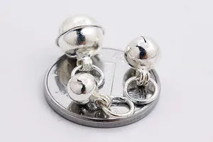 Three sizes of polished silver bell pendants next to a coin for size reference