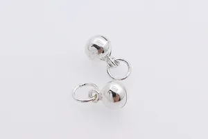 Close-up of polished silver ball pendants with closed rings for DIY jewelry making