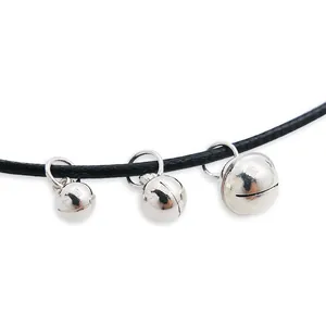 Three silver bell pendants with high mirror polish on a black braided cord on white background