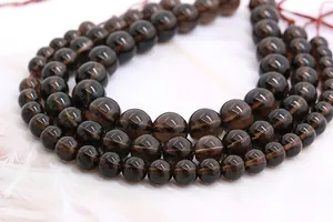 Makroaufnahme polierter Rauchquarz-Perlen für DIY-Schmuck mit eleganter weißer Feder