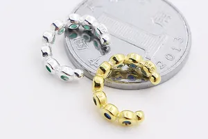 Dettaglio macro di orecchini in argento S925 con zirconi colorati accanto a una moneta