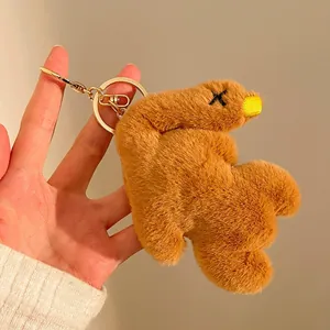 Macro detail of plush brown bear pendant with X-shaped embroidery and golden keychain