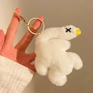 Detail showing the plush white duck keychain with golden metal clasp held in hand